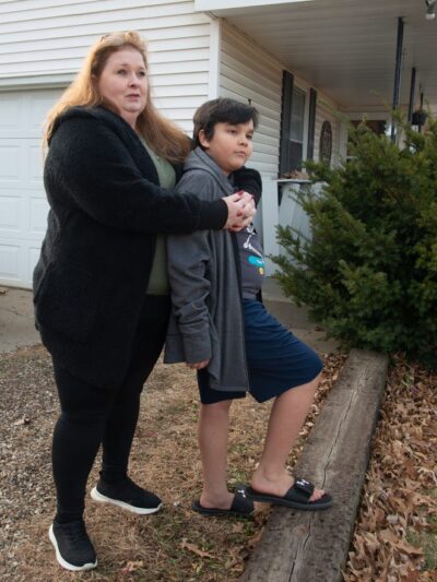 Brandy Carlson stands in yard with son, Michael