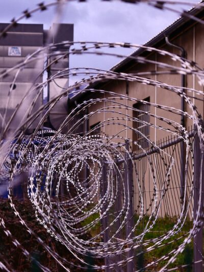 Barbed wire fence with prison in background