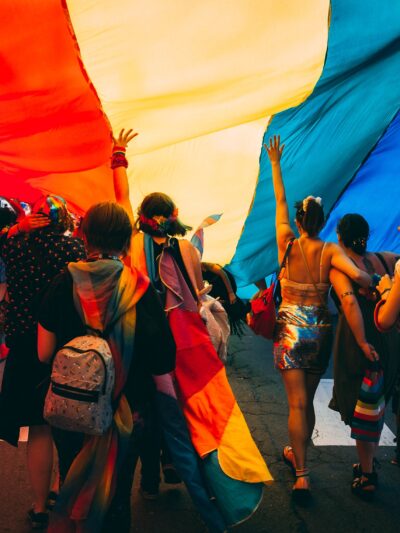 People marching under a rainbow parachute