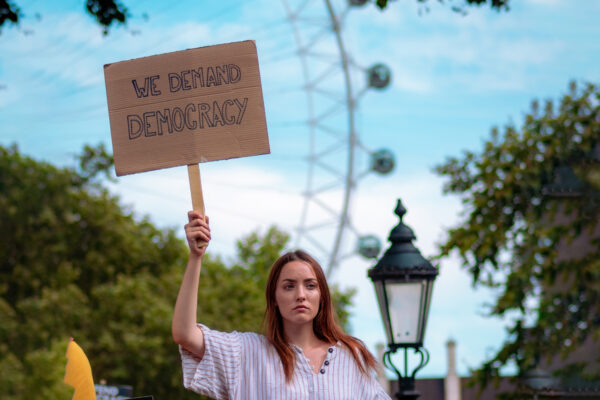 Woman holding a sign that says "We demand democracy"