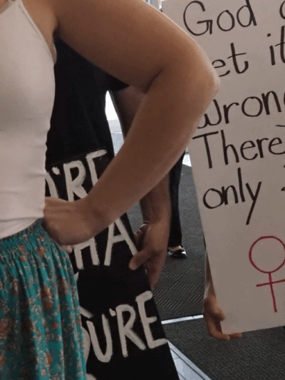 Halsey Yankey stands in front of a protester at a gender marker clinic held at the Lawrence Public Library on May 17, blocking his transphobic sign from view. (Rachel Mipro/Kansas Reflector)