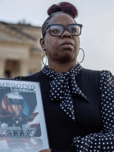 Christian Kelley showcases a framed photo of her brother Christopher DeVon Kelley in front of the Kansas Statehouse in Topeka. Officers shot and killed the Marine Corps veteran in June 2022. Emily Curiel