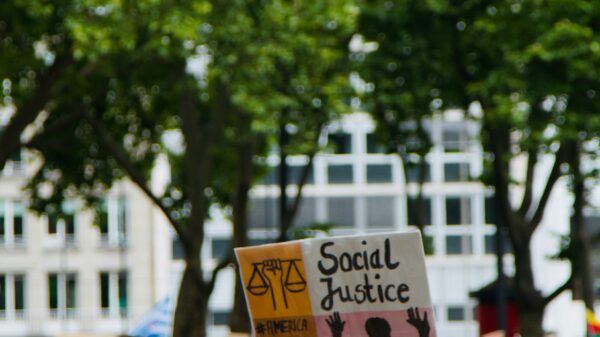 Photo of a rally, person holds sign that says "social justice"