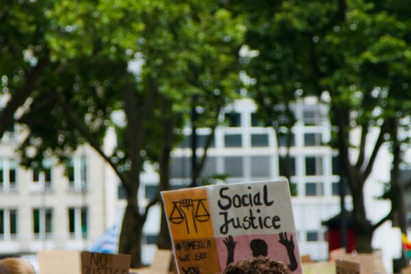 Photo of a rally, person holds sign that says "social justice"