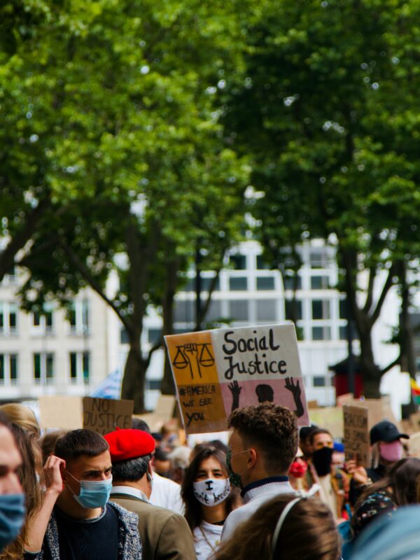 Photo of a rally, person holds sign that says "social justice"