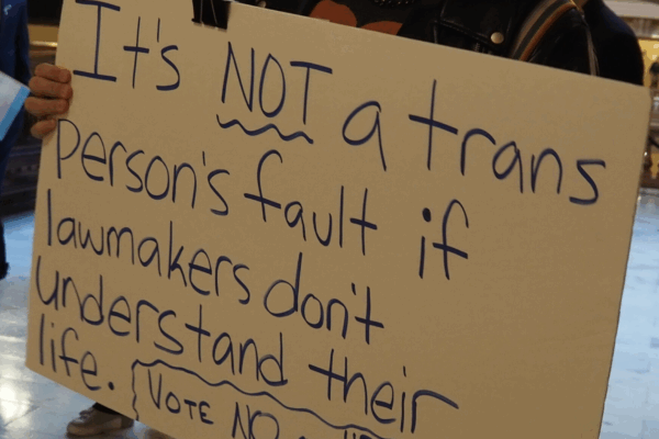 Activist Jae Moyer holds up a sign protesting new legislation that would restrict access to gender-affirming care in the state. (Rachel Mipro/Kansas Reflector)