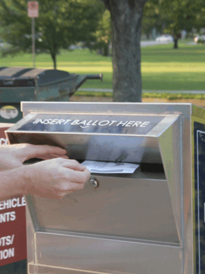 A voter drops a ballot into a dropbox at a polling site Aug. 6, 2024, in Lawrence. (Maya Smith for Kansas Reflector)