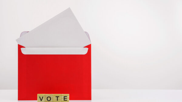An open envelope with scrabble tiles that spell out "vote"