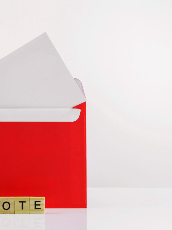 An open envelope with scrabble tiles that spell out "vote"