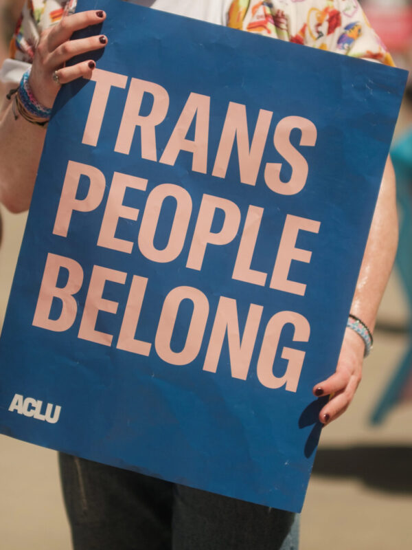 Person holding sign that says "Trans People Belong"