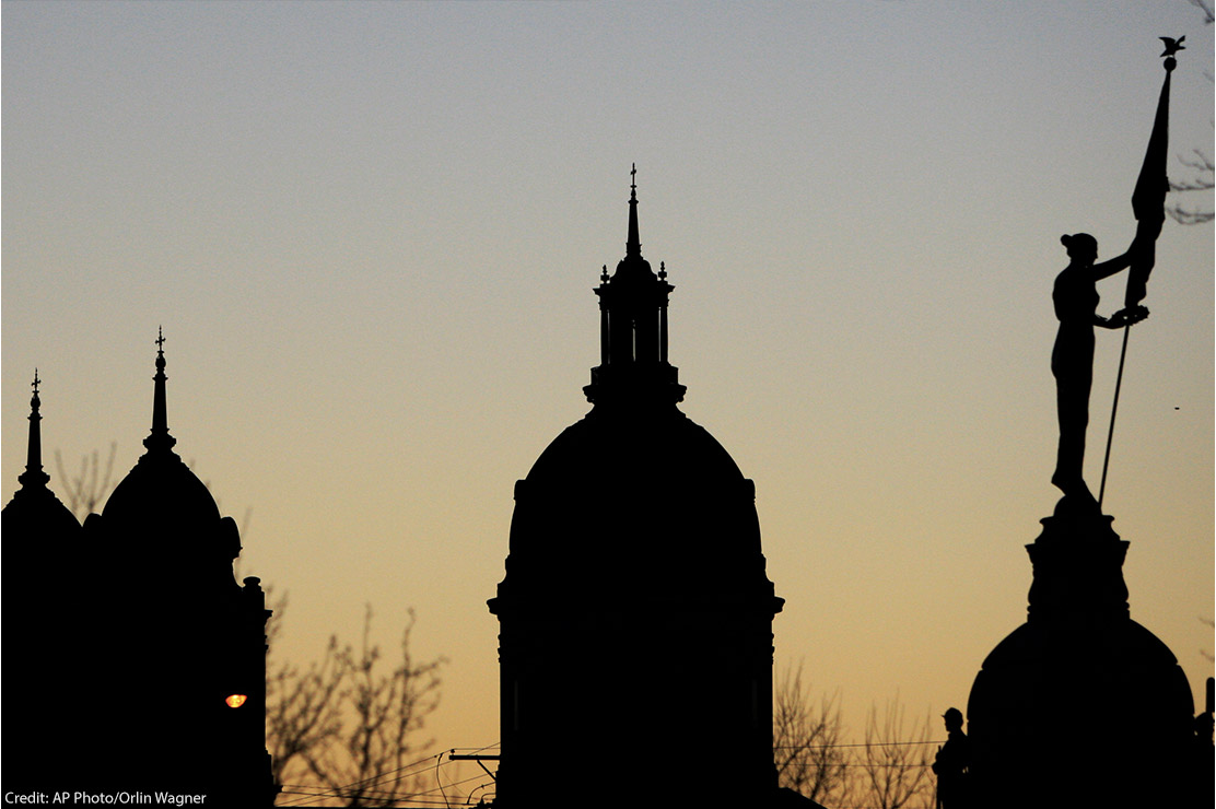 alt="Several buildings and monuments silhouetted against the early morning sky in Wichita, Kansas."