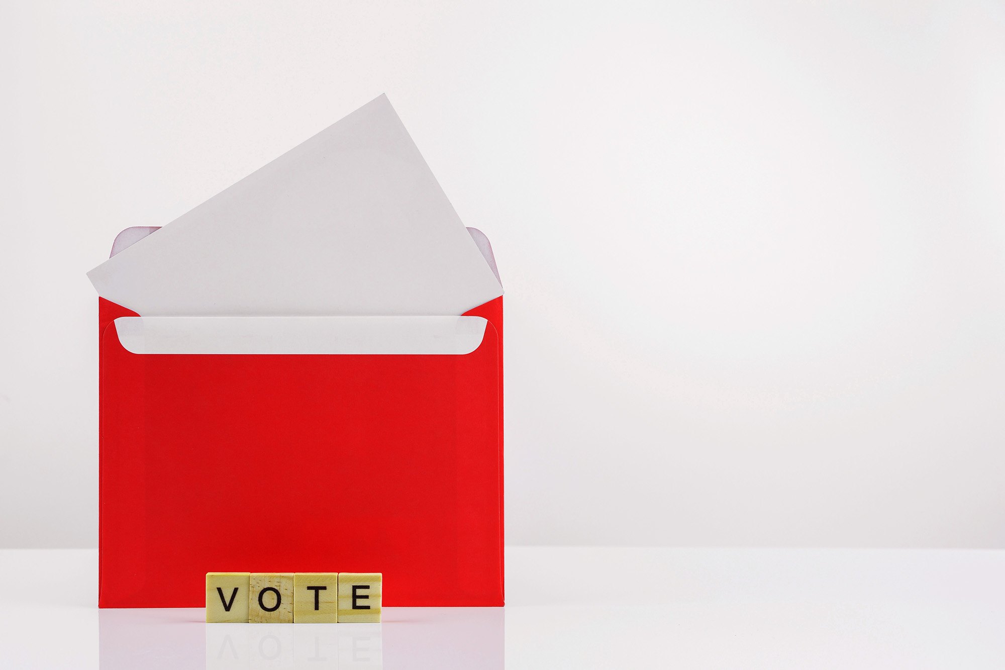 An open envelope with scrabble tiles that spell out "vote"