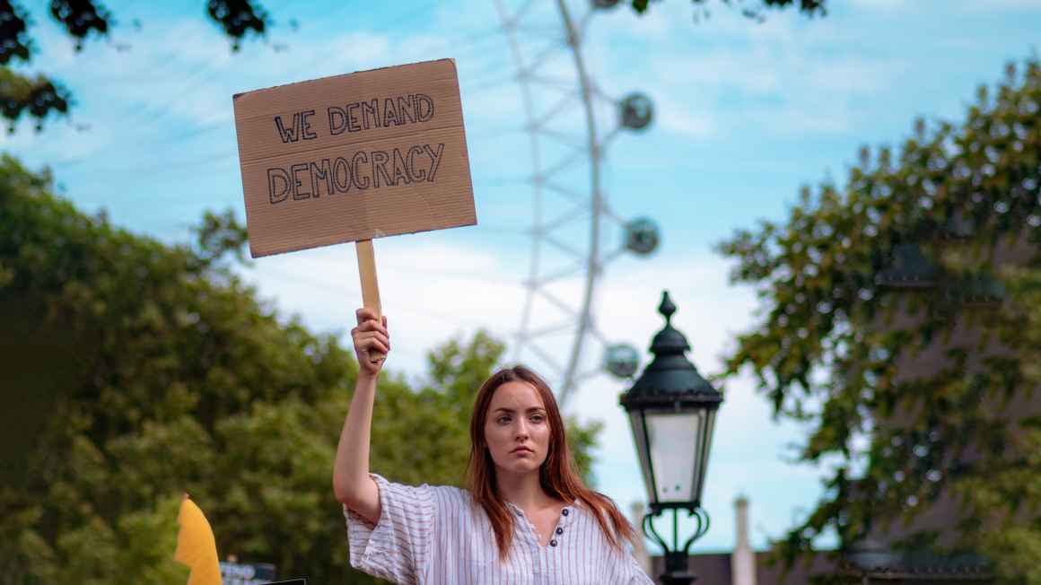 Woman holding a sign that says "We demand democracy"