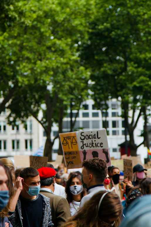 Photo of a rally, person holds sign that says "social justice"