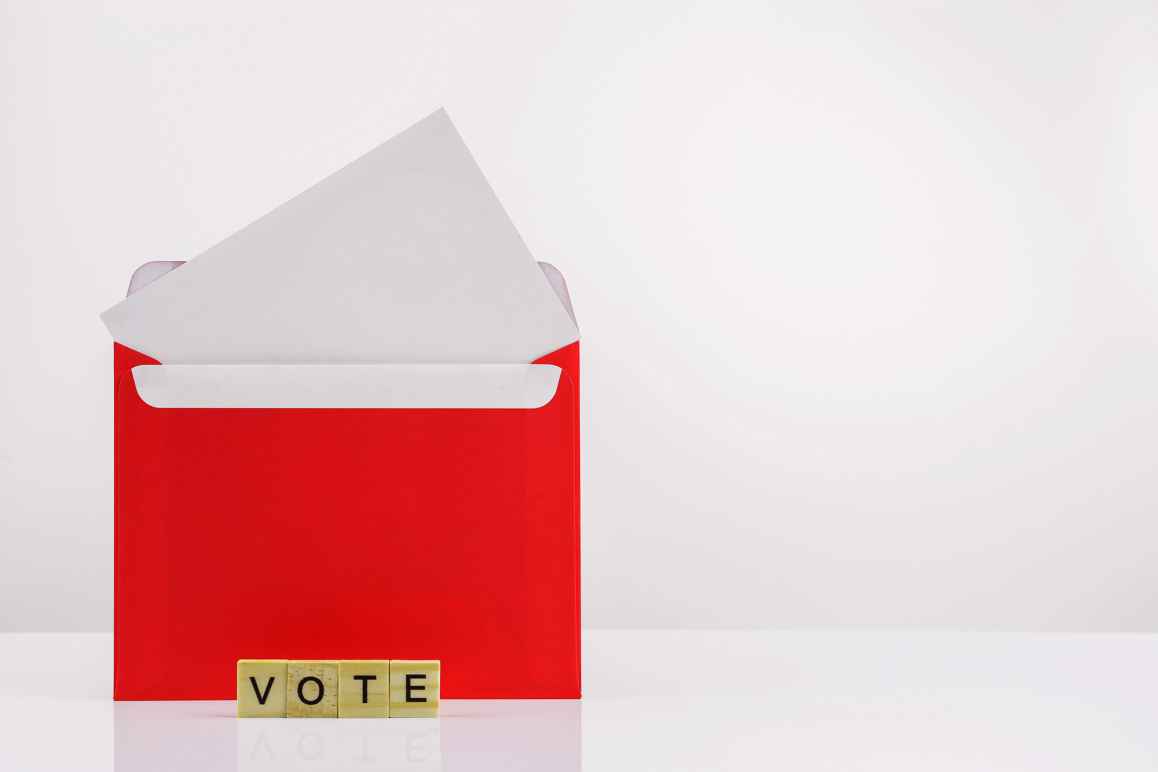 An open envelope with scrabble tiles that spell out "vote"