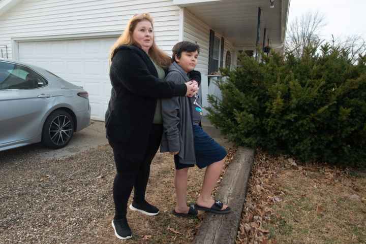 Brandy Carlson stands in yard with son, Michael
