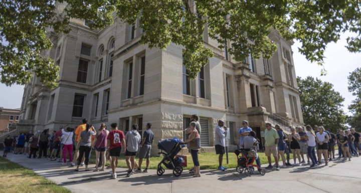 A long line of voters wraps around the Sedgwick County Historic Courthouse in Wichita, Kan., on the last day of early voting on Aug. 1, 2022. Kansas' top elections official warned voters Monday, Oct. 31, 2022, that text messages they were receiving could 