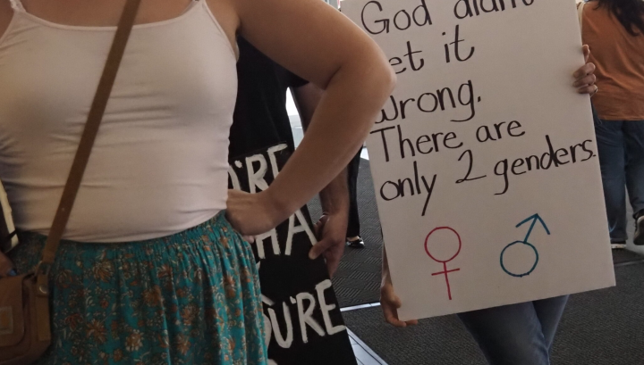  Halsey Yankey stands in front of a protester at a gender marker clinic held at the Lawrence Public Library on May 17, blocking his transphobic sign from view. (Rachel Mipro/Kansas Reflector)
