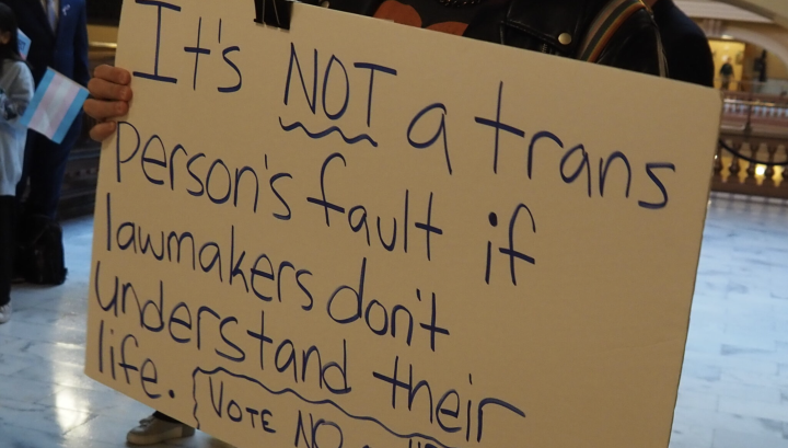 Activist Jae Moyer holds up a sign protesting new legislation that would restrict access to gender-affirming care in the state. (Rachel Mipro/Kansas Reflector)