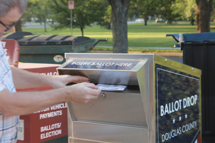  A voter drops a ballot into a dropbox at a polling site Aug. 6, 2024, in Lawrence. (Maya Smith for Kansas Reflector)