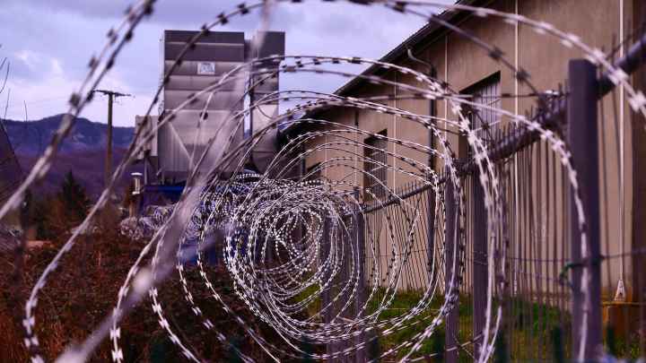 Barbed wire fence with prison in background
