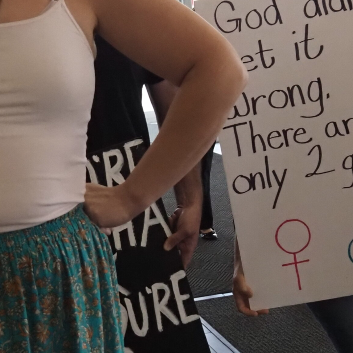 Halsey Yankey stands in front of a protester at a gender marker clinic held at the Lawrence Public Library on May 17, blocking his transphobic sign from view. (Rachel Mipro/Kansas Reflector)
