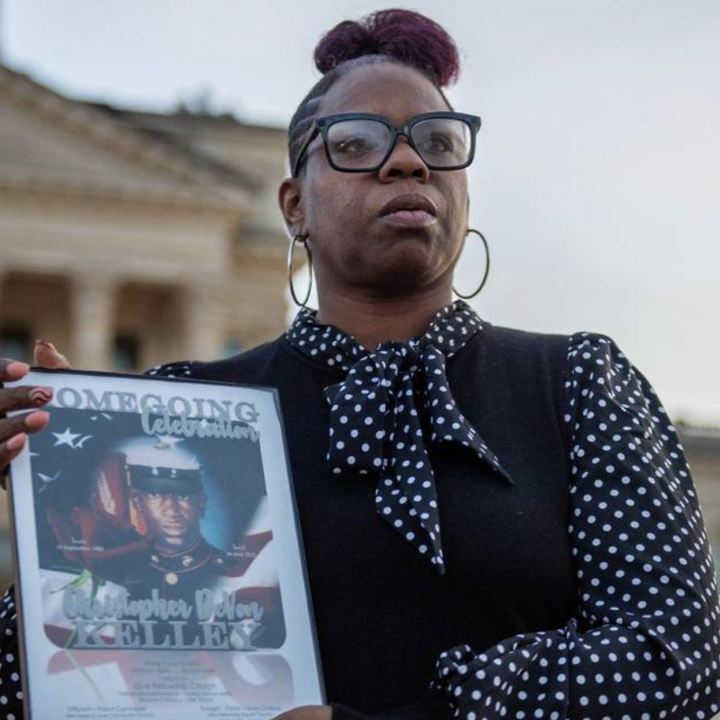 Christian Kelley showcases a framed photo of her brother Christopher DeVon Kelley in front of the Kansas Statehouse in Topeka. Officers shot and killed the Marine Corps veteran in June 2022. Emily Curiel