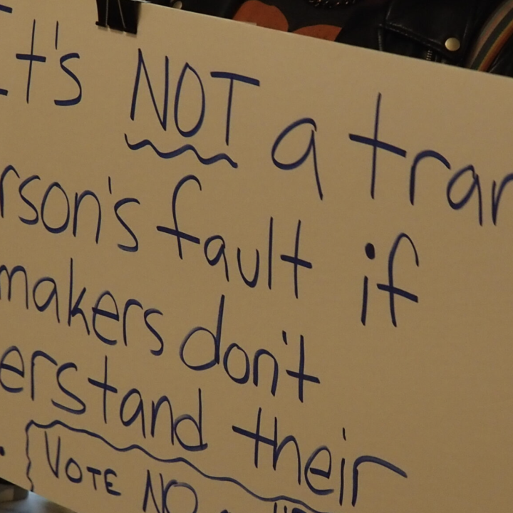 Activist Jae Moyer holds up a sign protesting new legislation that would restrict access to gender-affirming care in the state. (Rachel Mipro/Kansas Reflector)