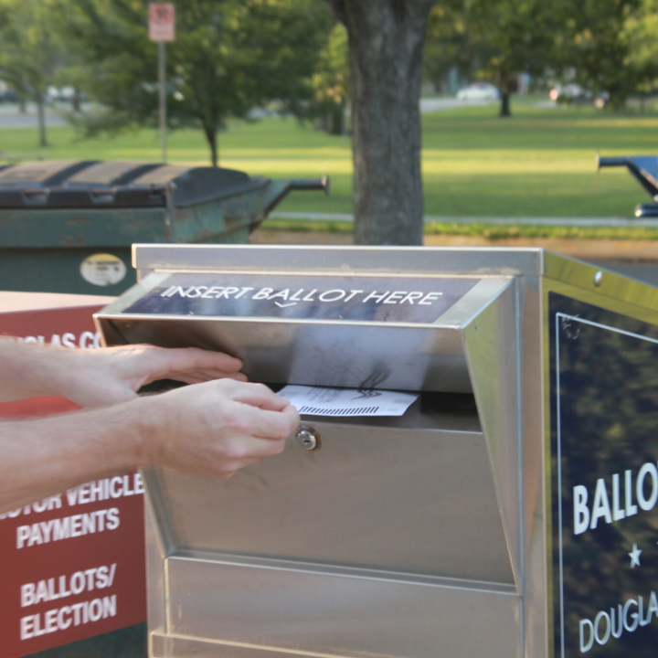  A voter drops a ballot into a dropbox at a polling site Aug. 6, 2024, in Lawrence. (Maya Smith for Kansas Reflector)