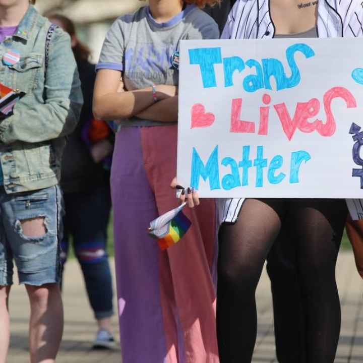 protestors with sign that says trans lives matter