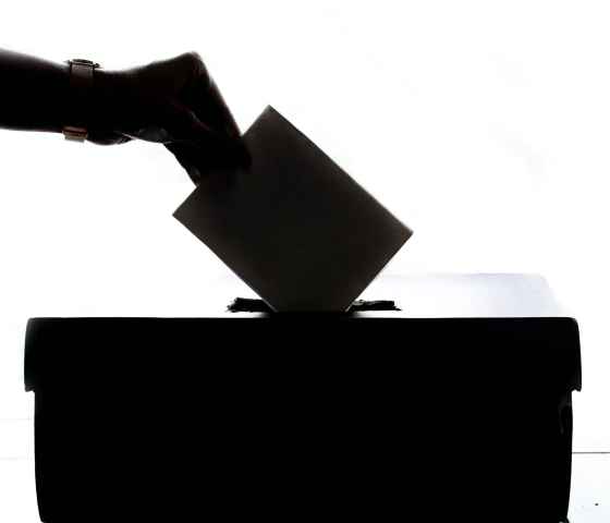 person putting ballot into ballot box